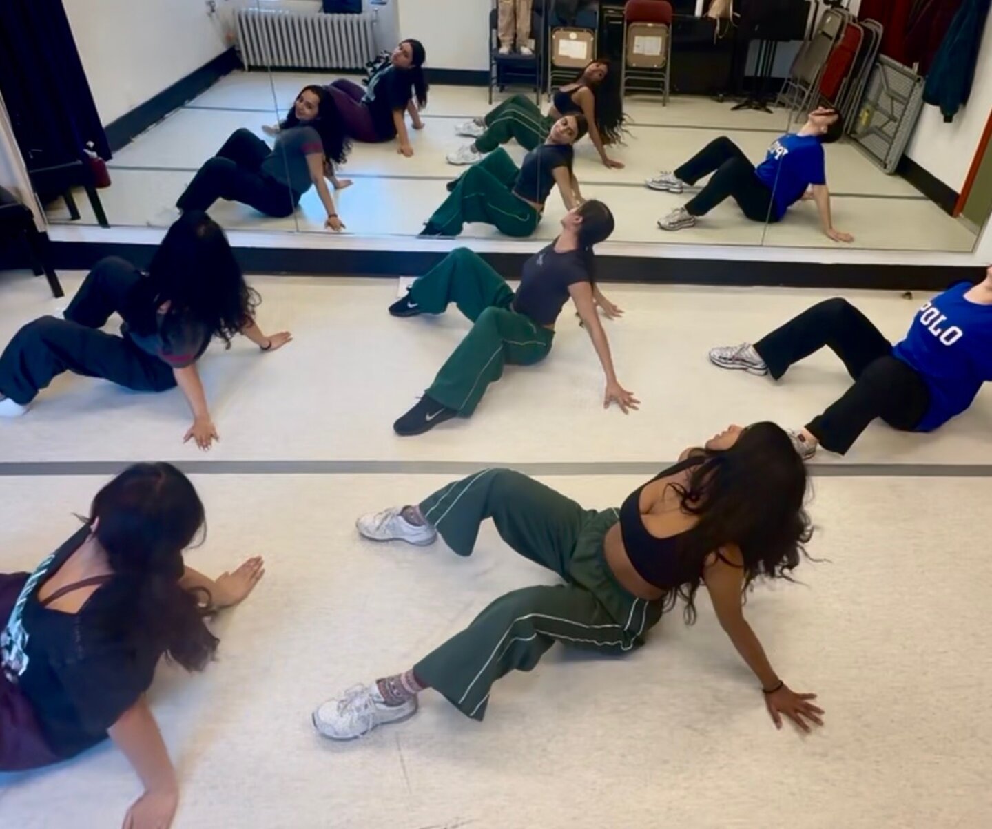 Dancers practicing floor choreography in a mirrored dance studio